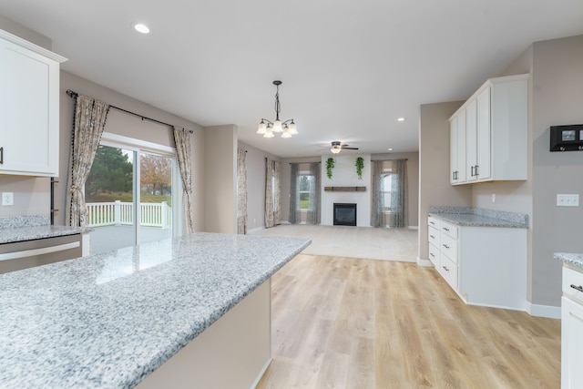 kitchen with pendant lighting, ceiling fan with notable chandelier, and white cabinetry