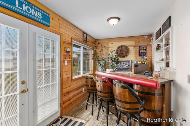 bar with light hardwood / wood-style flooring and wood walls