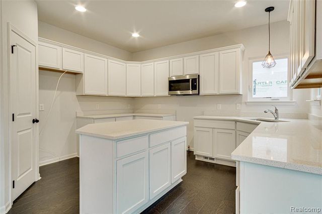 kitchen with pendant lighting, a center island, dark wood-type flooring, white cabinets, and sink