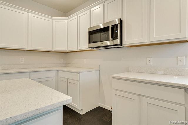 kitchen featuring light stone counters, dark hardwood / wood-style flooring, and white cabinets