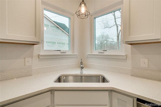 kitchen with a wealth of natural light, sink, white cabinets, and pendant lighting