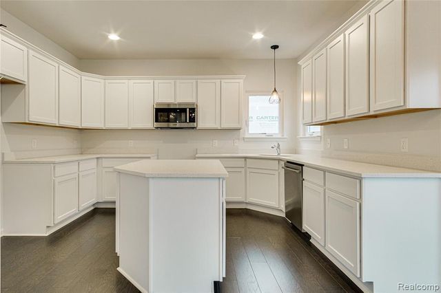 kitchen with white cabinetry, dark hardwood / wood-style floors, decorative light fixtures, a kitchen island, and appliances with stainless steel finishes