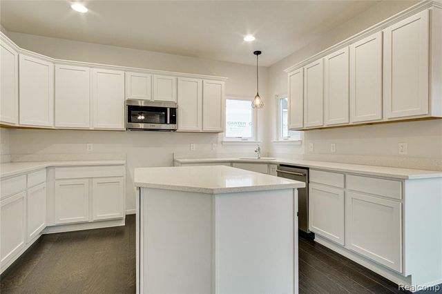 kitchen with dark wood-type flooring, sink, hanging light fixtures, white cabinetry, and stainless steel appliances