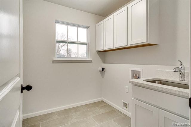 laundry area with hookup for a washing machine, sink, light tile patterned floors, and cabinets