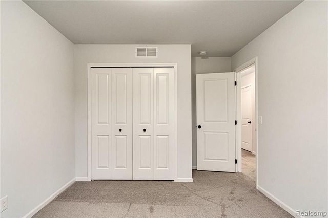 unfurnished bedroom featuring light carpet and a closet