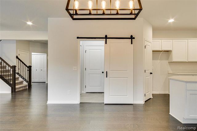 kitchen featuring a barn door, white cabinets, pendant lighting, and dark hardwood / wood-style floors