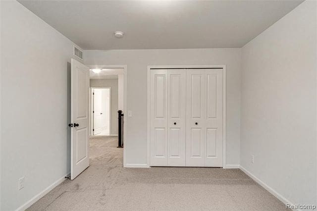 unfurnished bedroom featuring light colored carpet and a closet