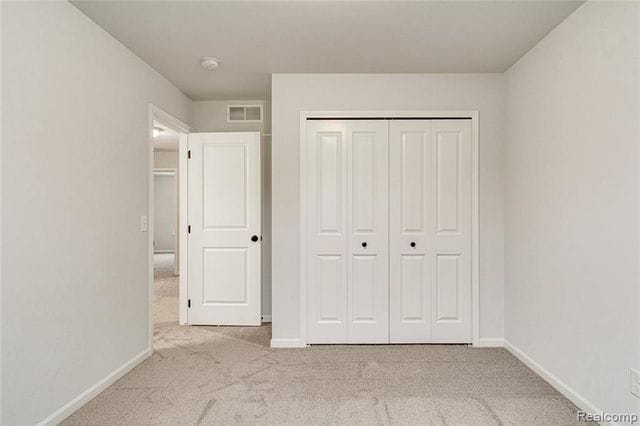 unfurnished bedroom featuring light carpet and a closet