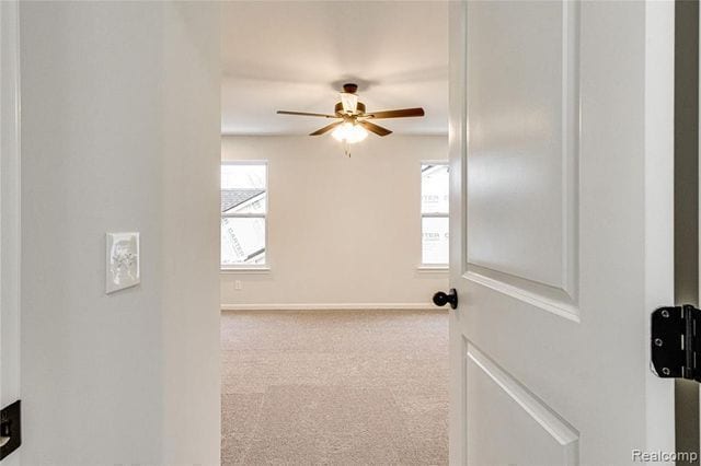 unfurnished room with light colored carpet and ceiling fan