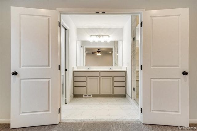 bathroom with an enclosed shower, vanity, and ceiling fan