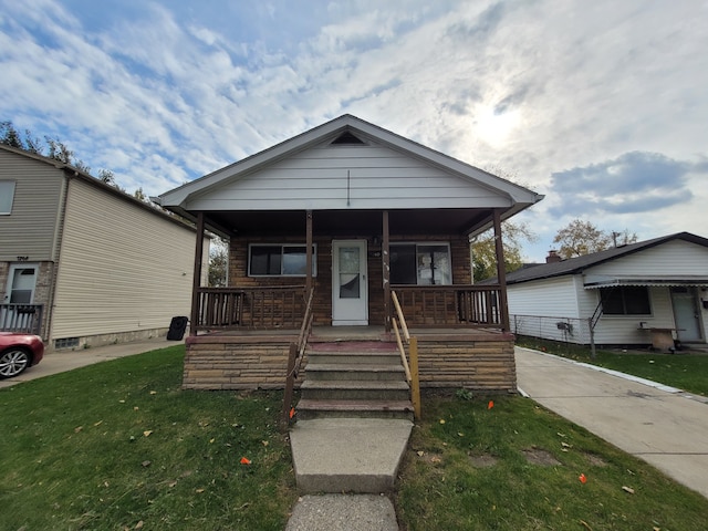 bungalow with covered porch and a front yard