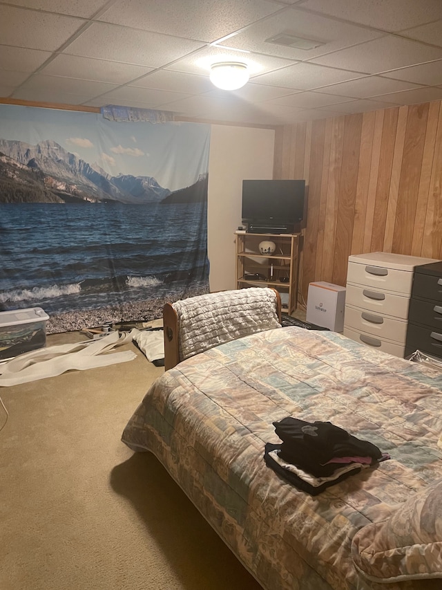 bedroom with a paneled ceiling, wood walls, and carpet floors