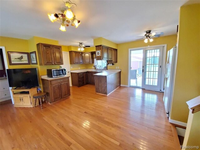 kitchen with white refrigerator with ice dispenser, a center island, light hardwood / wood-style flooring, and sink