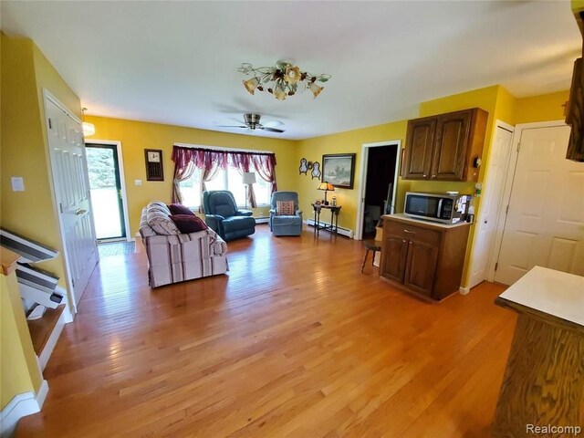 living room with a baseboard radiator, light hardwood / wood-style flooring, and ceiling fan