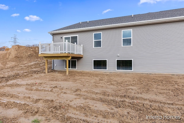 back of property featuring a shingled roof and a deck