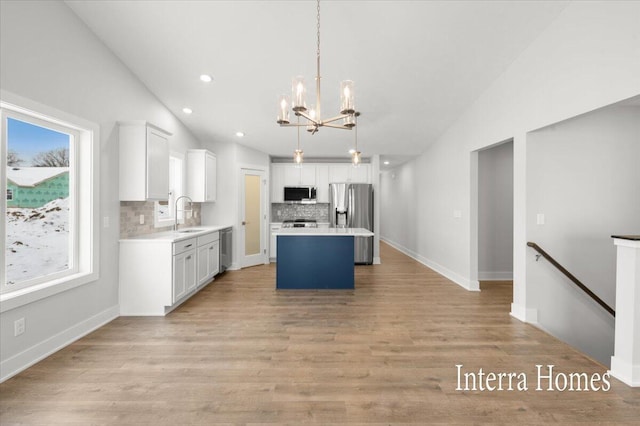 kitchen featuring lofted ceiling, light countertops, white cabinets, appliances with stainless steel finishes, and a chandelier