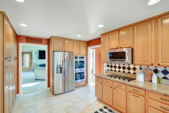 kitchen with decorative backsplash, light tile patterned floors, light stone countertops, and appliances with stainless steel finishes