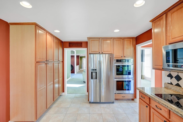 kitchen with light tile patterned flooring, light stone counters, and stainless steel appliances