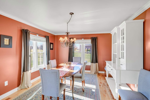 dining room featuring a chandelier, light hardwood / wood-style flooring, and crown molding