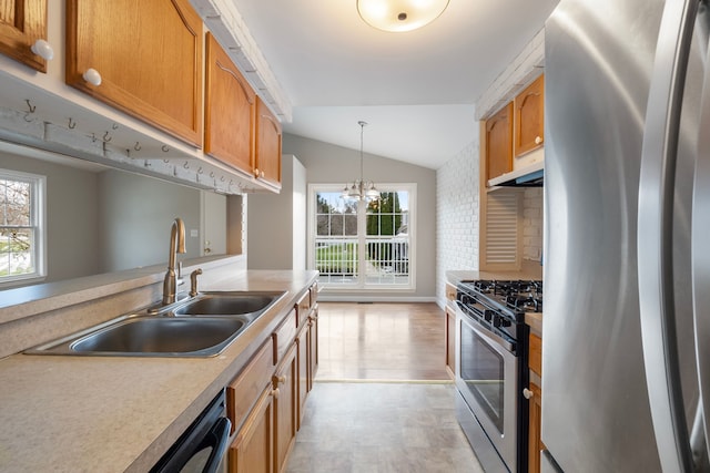 kitchen with stainless steel appliances, sink, pendant lighting, a notable chandelier, and lofted ceiling