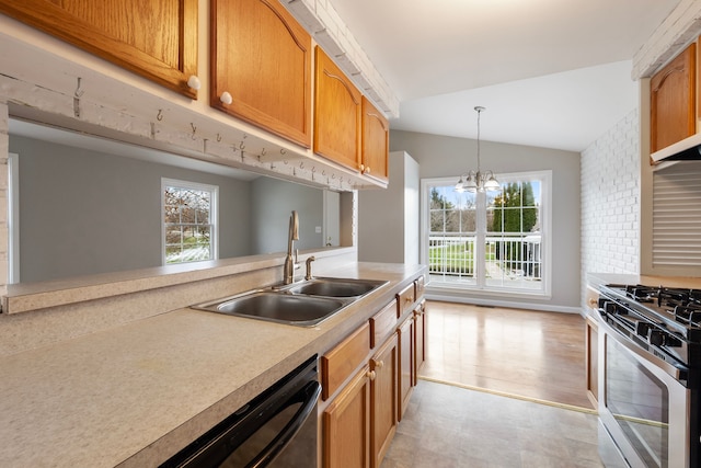 kitchen with appliances with stainless steel finishes, vaulted ceiling, sink, light hardwood / wood-style flooring, and a notable chandelier