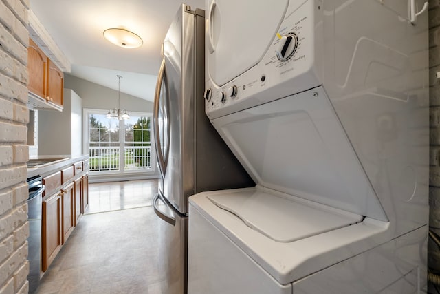 washroom featuring a notable chandelier and stacked washer / dryer