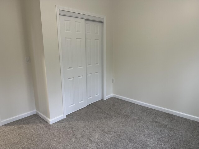 1820 S Reid Rd, Custer, MI 49405 - unfurnished bedroom with dark colored carpet, a closet, and baseboards