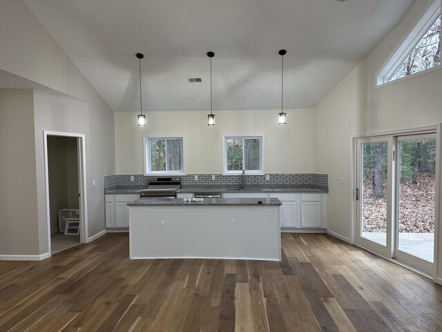 1820 S Reid Rd, Custer, MI 49405 - kitchen featuring high vaulted ceiling, backsplash, white cabinets, a kitchen island, and dark wood-style flooring