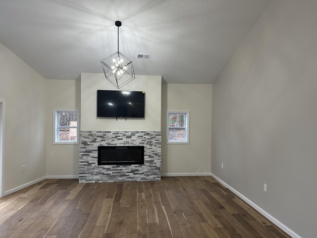 1820 S Reid Rd, Custer, MI 49405 - unfurnished living room featuring wood finished floors, a chandelier, baseboards, lofted ceiling, and a glass covered fireplace