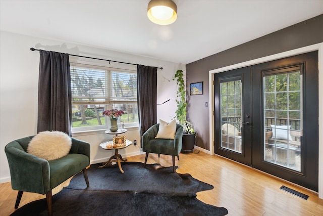 sitting room with plenty of natural light, french doors, and light wood-type flooring