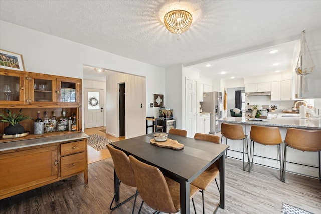 dining area featuring a textured ceiling, light hardwood / wood-style floors, and sink