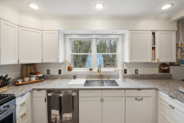 kitchen with light stone countertops, sink, crown molding, white cabinets, and appliances with stainless steel finishes