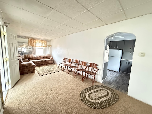 carpeted living room featuring a paneled ceiling and ceiling fan