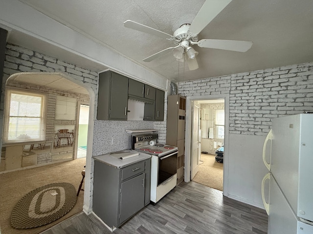 kitchen featuring gray cabinetry, light wood-type flooring, white appliances, and a textured ceiling