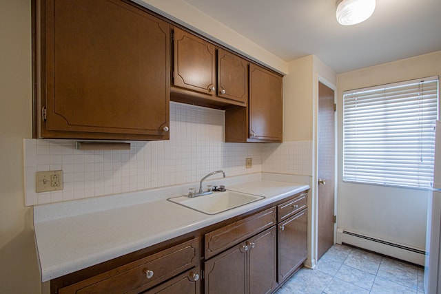 kitchen featuring backsplash, sink, light tile patterned floors, and a baseboard heating unit