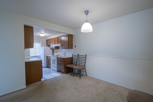 kitchen with light carpet, decorative backsplash, white appliances, wooden walls, and pendant lighting