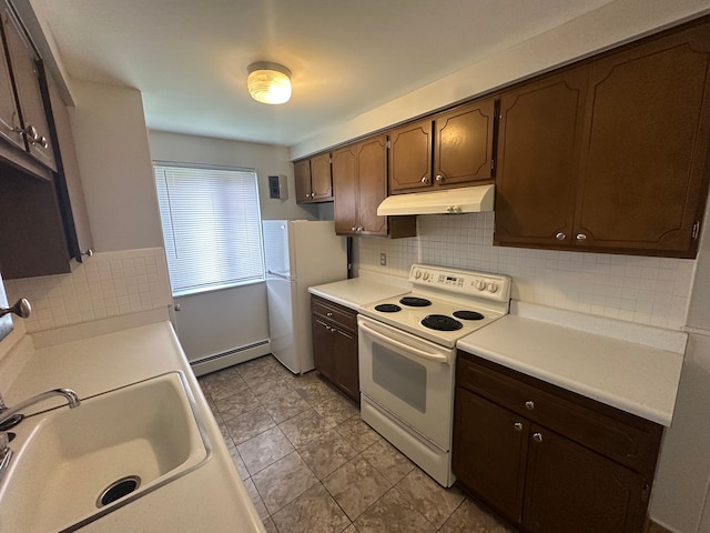 kitchen with decorative backsplash, a baseboard heating unit, under cabinet range hood, and white appliances