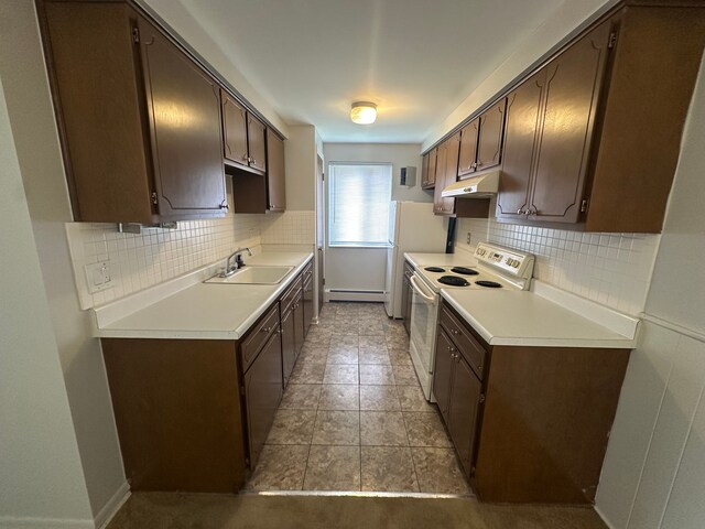 kitchen with white appliances, dark brown cabinetry, under cabinet range hood, and a sink