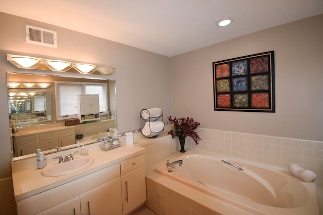 bathroom with tiled tub and vanity