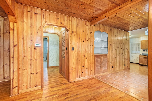 corridor with beamed ceiling, light hardwood / wood-style floors, wood ceiling, and wood walls