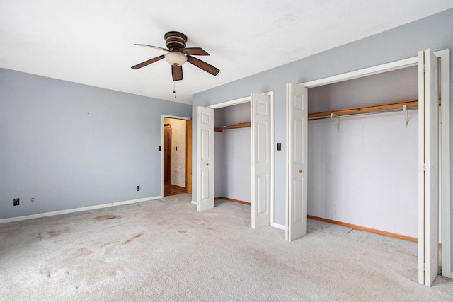 unfurnished bedroom with ceiling fan, light colored carpet, and multiple closets