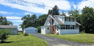 view of front of property featuring a front yard, an outbuilding, and a garage