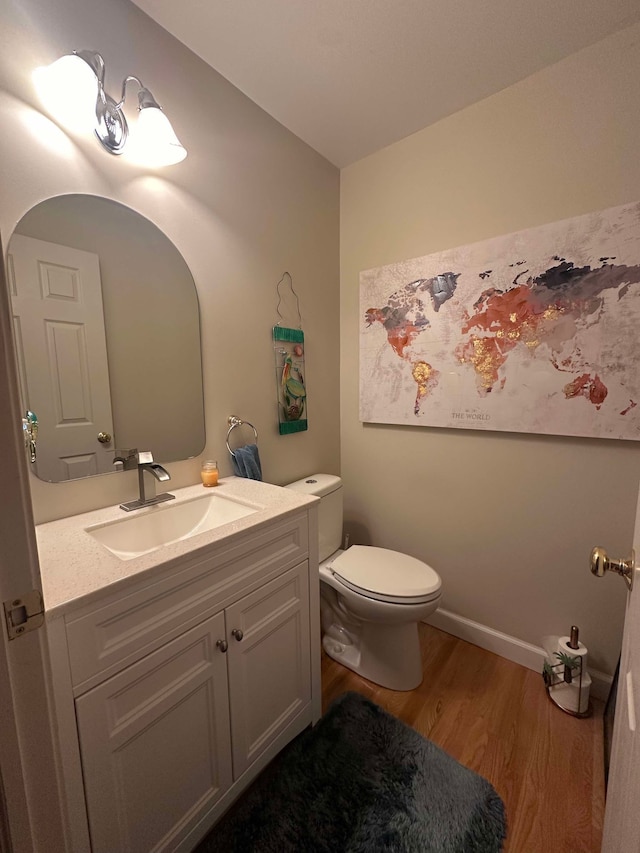 bathroom with wood-type flooring, vanity, and toilet