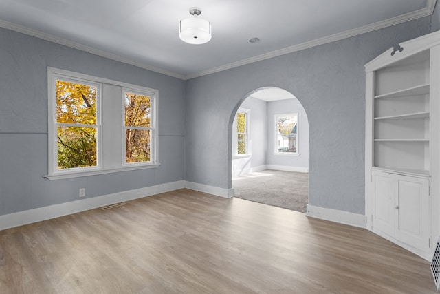 unfurnished room featuring built in features, crown molding, and light hardwood / wood-style flooring