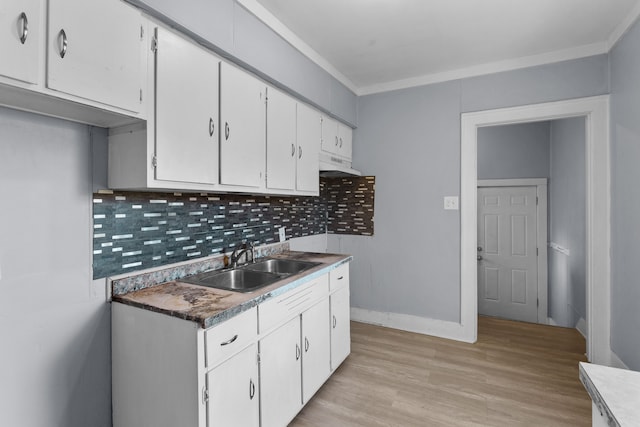 kitchen with white cabinets, light hardwood / wood-style floors, sink, and tasteful backsplash