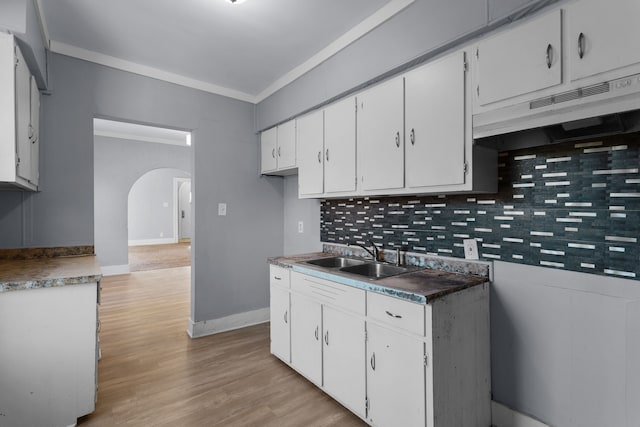 kitchen featuring white cabinetry, sink, tasteful backsplash, light wood-type flooring, and ornamental molding