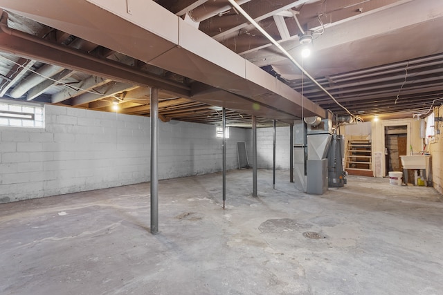 basement with heating unit, water heater, and sink