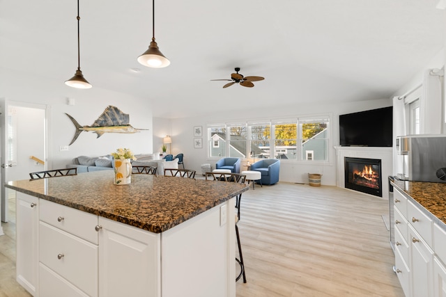 kitchen with white cabinetry, a center island, pendant lighting, a breakfast bar area, and light wood-type flooring