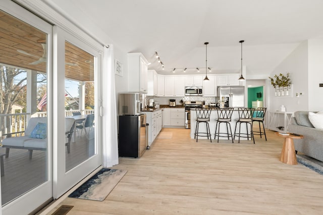 kitchen with pendant lighting, backsplash, a kitchen breakfast bar, white cabinetry, and stainless steel appliances