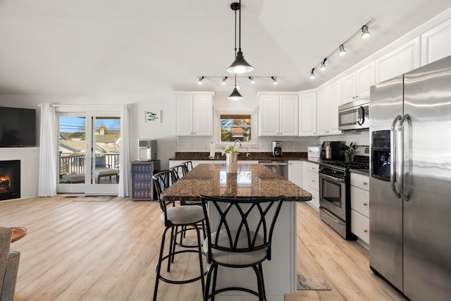 kitchen featuring a kitchen island, stainless steel appliances, white cabinetry, and a healthy amount of sunlight